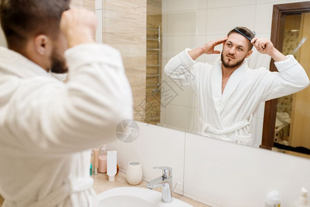 穿浴袍的男子在浴室梳理头发图片
