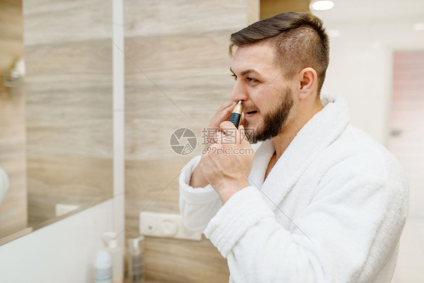 穿浴袍的男子在浴室用工具摘鼻毛图片
