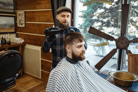 专业理发店是一种时髦的职业男理发师和客户在倒型发廊中做理师和用梳子做型图片