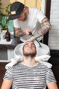 年轻男子在理发店洗头客户头部理发师用毛巾擦客户头部图片