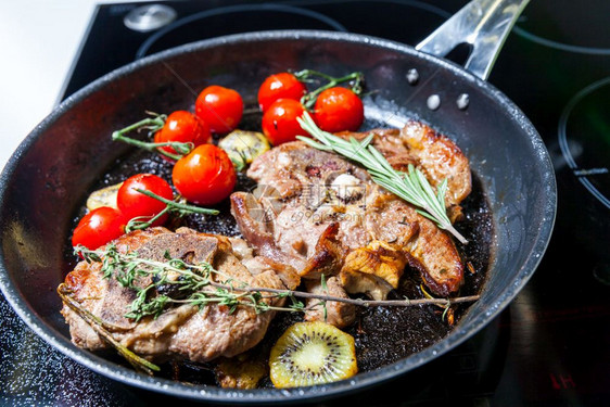 男人在餐桌上用电炉煮猪肉男人在锅里用蔬菜煮肉图片