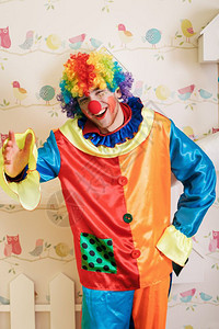 在游戏室里站着装饰鸟和巢穴在背景上严肃的小丑在搞笑服装里图片