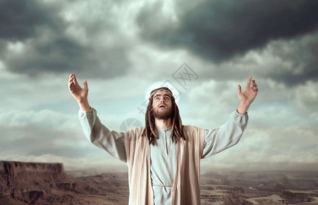 身穿白袍的基督手举起来对着阴云的天空祈祷坚定信仰上帝基督手举对着阴云的天空祈祷图片