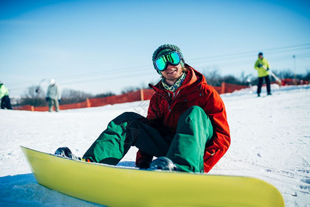 在雪坡上坐着的滑雪运动者图片