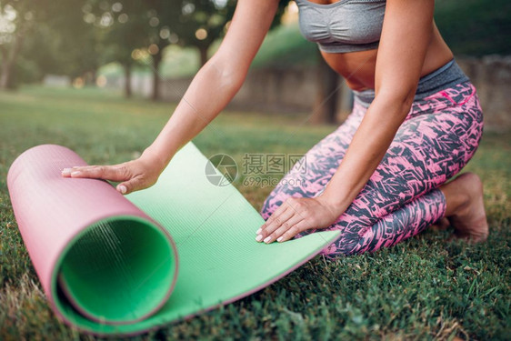 女青年在公园里使用瑜伽垫进行户外运动图片