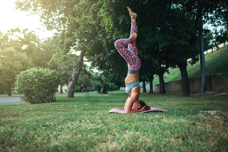 女青年在公园里使用瑜伽垫进行户外运动倒立图片