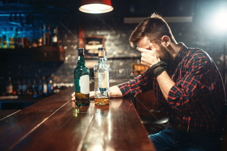 酒吧柜台坐着一个悲伤的男子