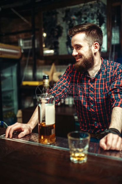 一个人手里拿着一瓶酒精饮料站在吧台旁酒吧里的男人酗酒酗酒一个人站在吧台旁喝醉了图片