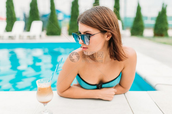 在游泳边喝鸡尾酒的年轻女孩图片