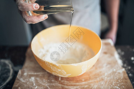 男人面包师给面粉加食用油图片