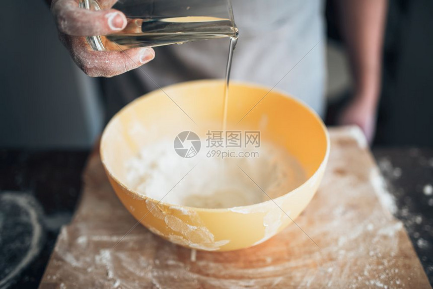 男人面包师给面粉加食用油图片