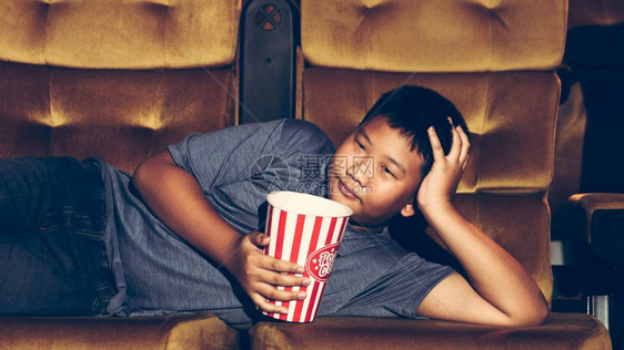 男孩躺着看电影开心地吃爆米图片