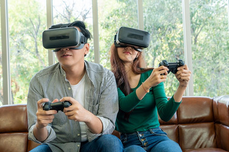 年轻快乐亚裔夫妇在客厅玩电子游戏图片