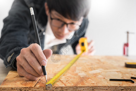 木匠仔细研究工程计划他是在工作场所成功的创业者在与切割工一起的建筑地作上打钉子图片