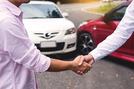 客户在车祸后同意就公路保险条款达成友好协议后与检查车祸主的汽保险代理商握手图片