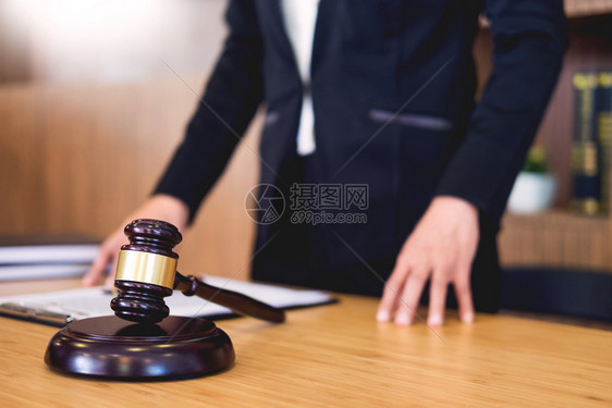 法官在审判室的书桌上宣读文件手持木制书桌背景手握黄金重量和声势司法障碍图片