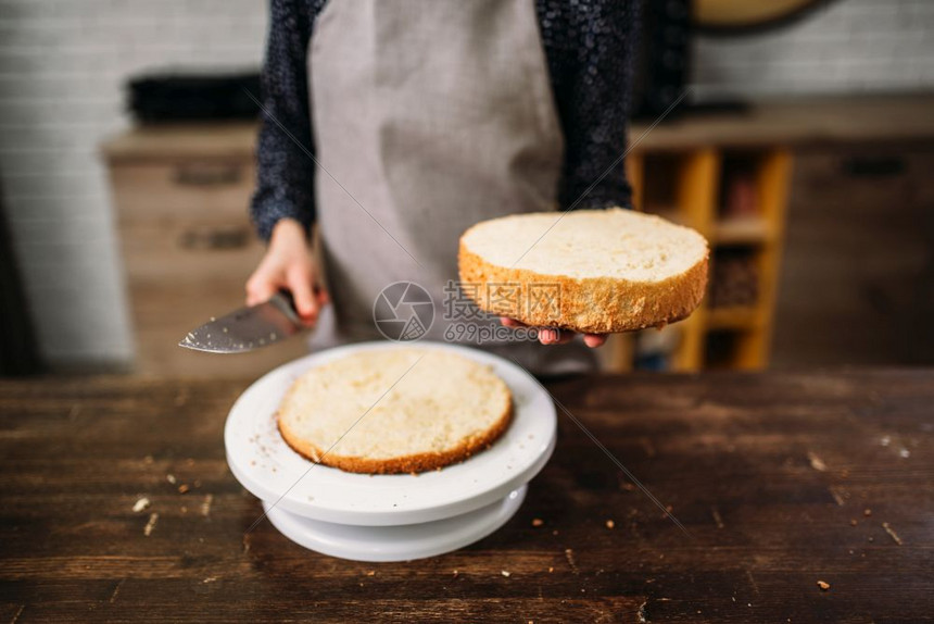 女人做饭手握着蛋糕和刀子木桌上自制甜点图片