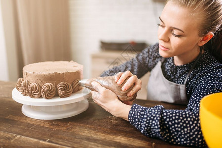 烹饪女厨用注射器装饰巧克力蛋糕厨房背景自制甜品装饰图片