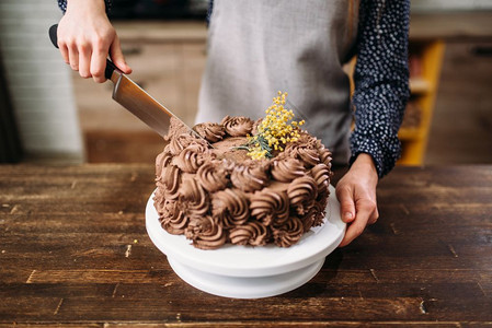 女手用刀切巧克力蛋糕烹饪杰作图片