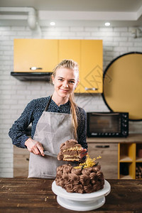 烹饪女人拿着一块巧克力蛋糕在刀片上烹饪杰作厨房在背景上自制甜点图片