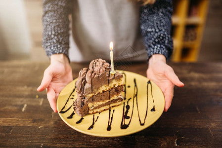 男人手握着一块蛋糕盘子装饰着蜡烛和巧克力酱烹饪杰作图片