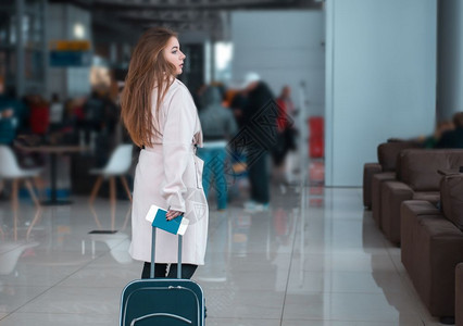年轻女旅行在机场大厅拖着行李箱行走图片