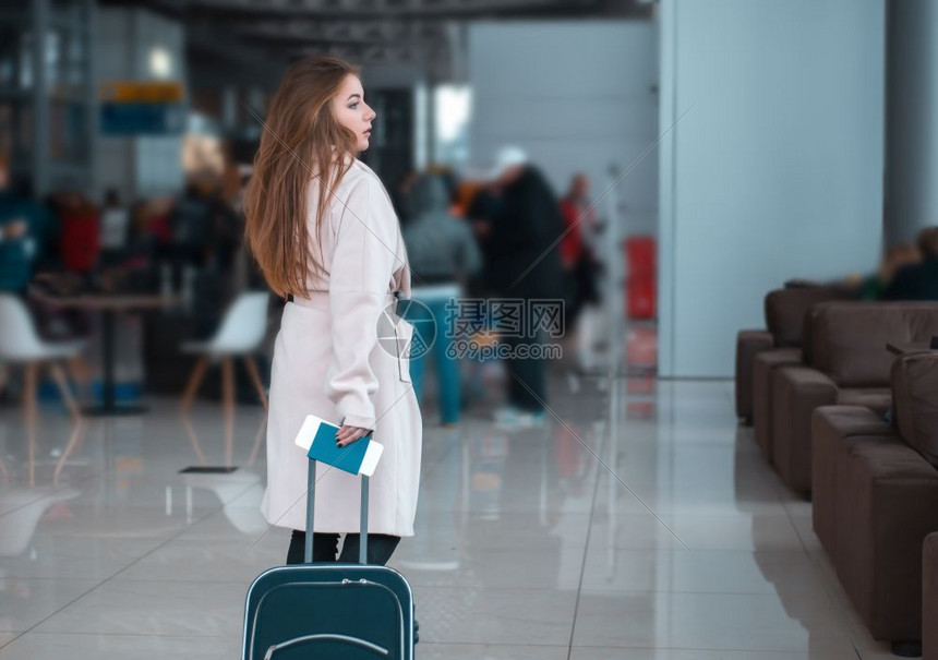年轻女旅行在机场大厅拖着行李箱行走图片