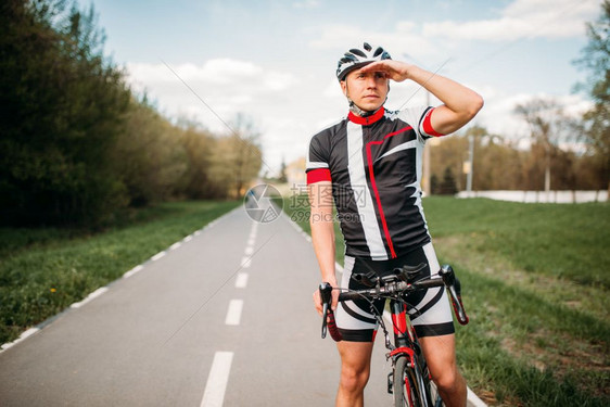 戴着头盔和穿着运动服的自行车运动员看向远方图片