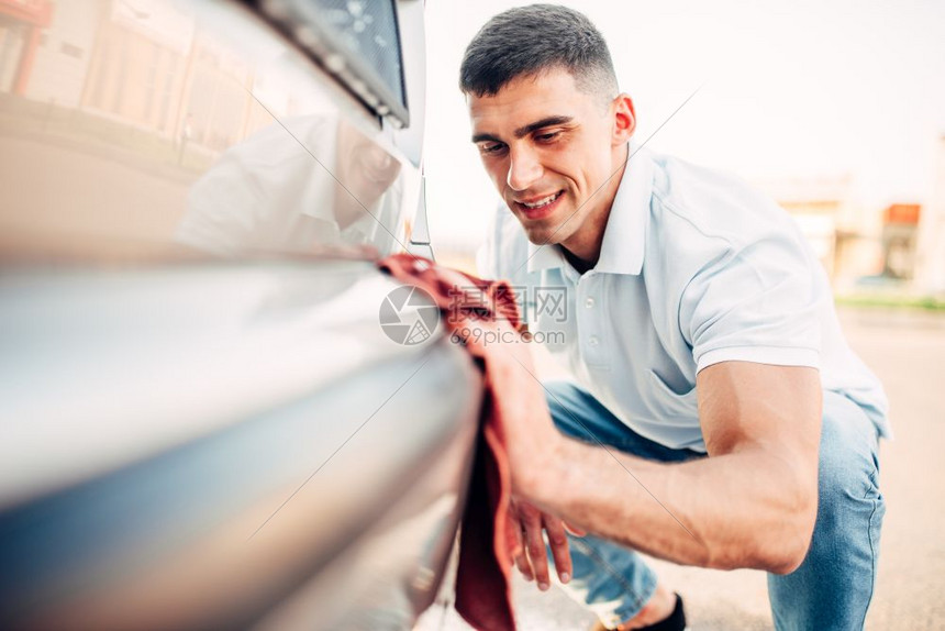 男子正在擦拭汽车图片