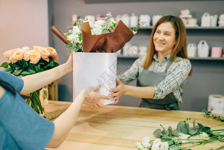 花店为的女顾客提供花瓶中的鲜成分图片