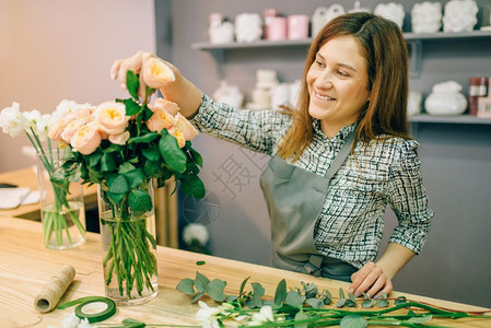 女花匠在店的瓶里放鲜玫瑰花卉图片