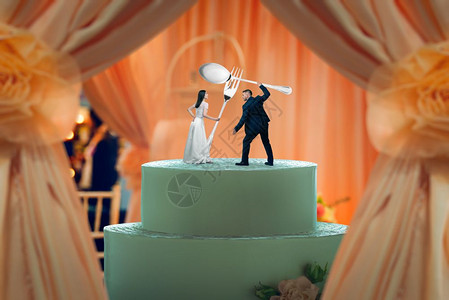 结婚蛋糕新娘和新郎雕像手顶上握着巨大的餐具图片