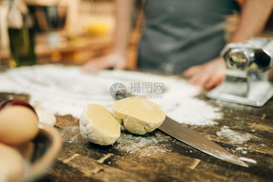 男厨师在木制房桌上用意面机工作图片