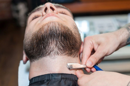 理发师与剃须刀一起在沙龙工作图片