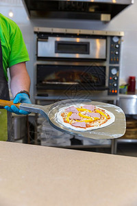 面包师手用铲子做饭比萨电烤炉图片