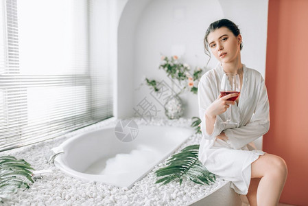 女子坐在浴池边上喝红酒图片