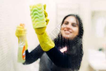 身戴手套的女佣用清洁喷雾洗玻璃在旅馆手间用背面图片