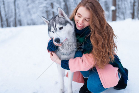 下雪的冬天年轻女子带着狗狗在公园一起在户外图片