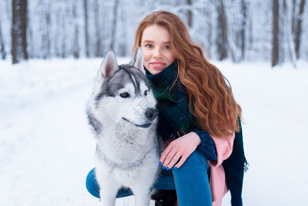 下雪的冬天年轻女子带着狗狗在公园一起在户外图片