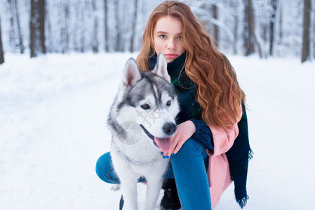 下雪的冬天年轻女子带着狗狗在公园一起在户外图片