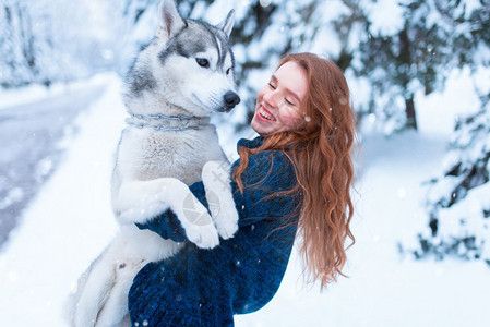 下雪的冬天年轻女子带着狗狗在公园一起在户外图片