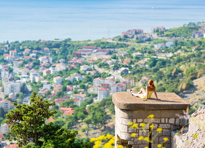 快乐的女孩坐在城市上仰望着大海图片素材