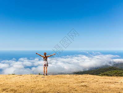 女人举起手站在山顶上脚下的女人顶图片