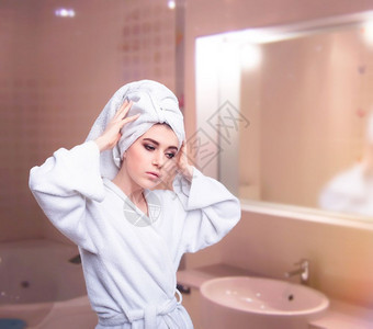 穿着浴袍的美女头上披着毛巾的部照顾她发在浴室里照镜子图片