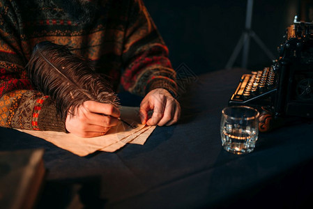 男子用羽毛在旧纸上写作图片