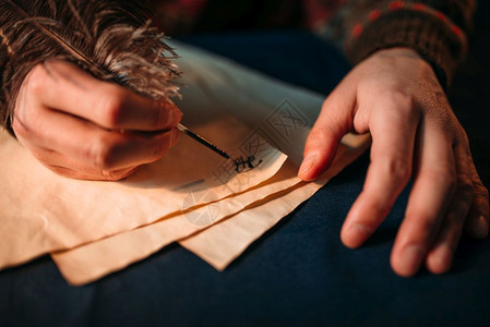 男人用羽毛笔在旧纸上写作图片