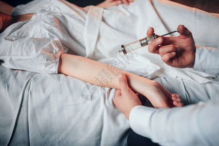 男医生用注射器对着病床上的女病人图片