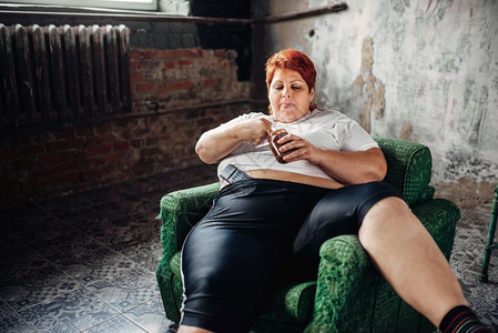 超重的女人坐在椅子上吃甜食图片