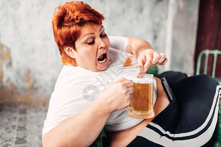 体重超的女人喝啤酒吃三明治食图片