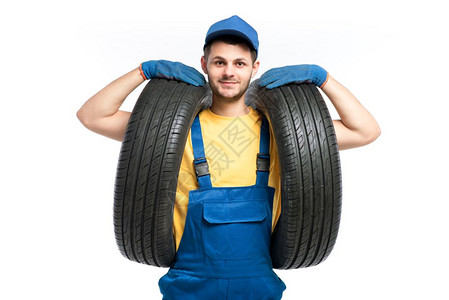 穿蓝色制服的轮胎工人手持汽车轮胎图片